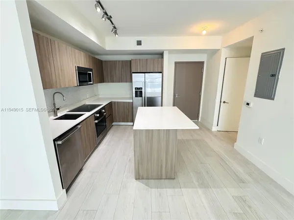 a large kitchen with a sink and refrigerator