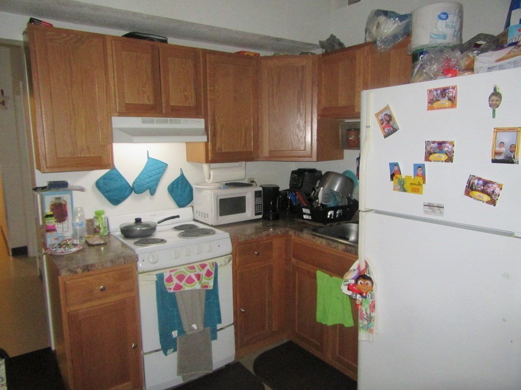 47 White Street Springfield, MA 01108 - Photo 6 of 16 a kitchen with a refrigerator a stove a sink a washer dryer and cabinets