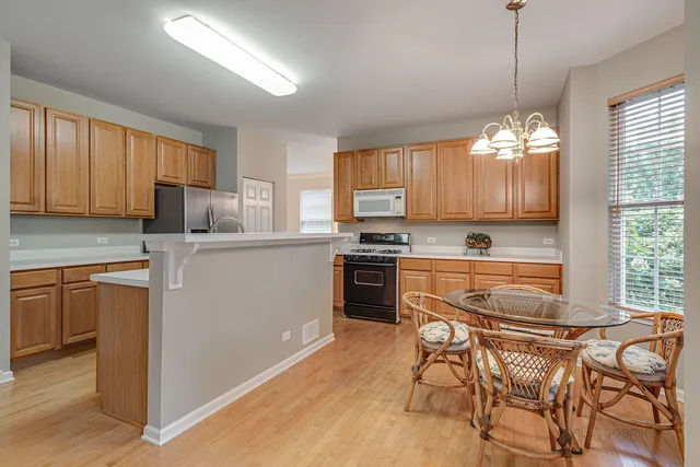 a kitchen with a refrigerator a stove cabinets and a dining table
