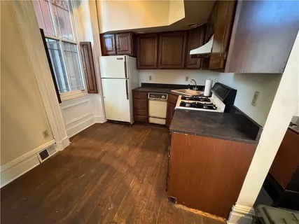 a kitchen with a refrigerator a stove and wooden floor