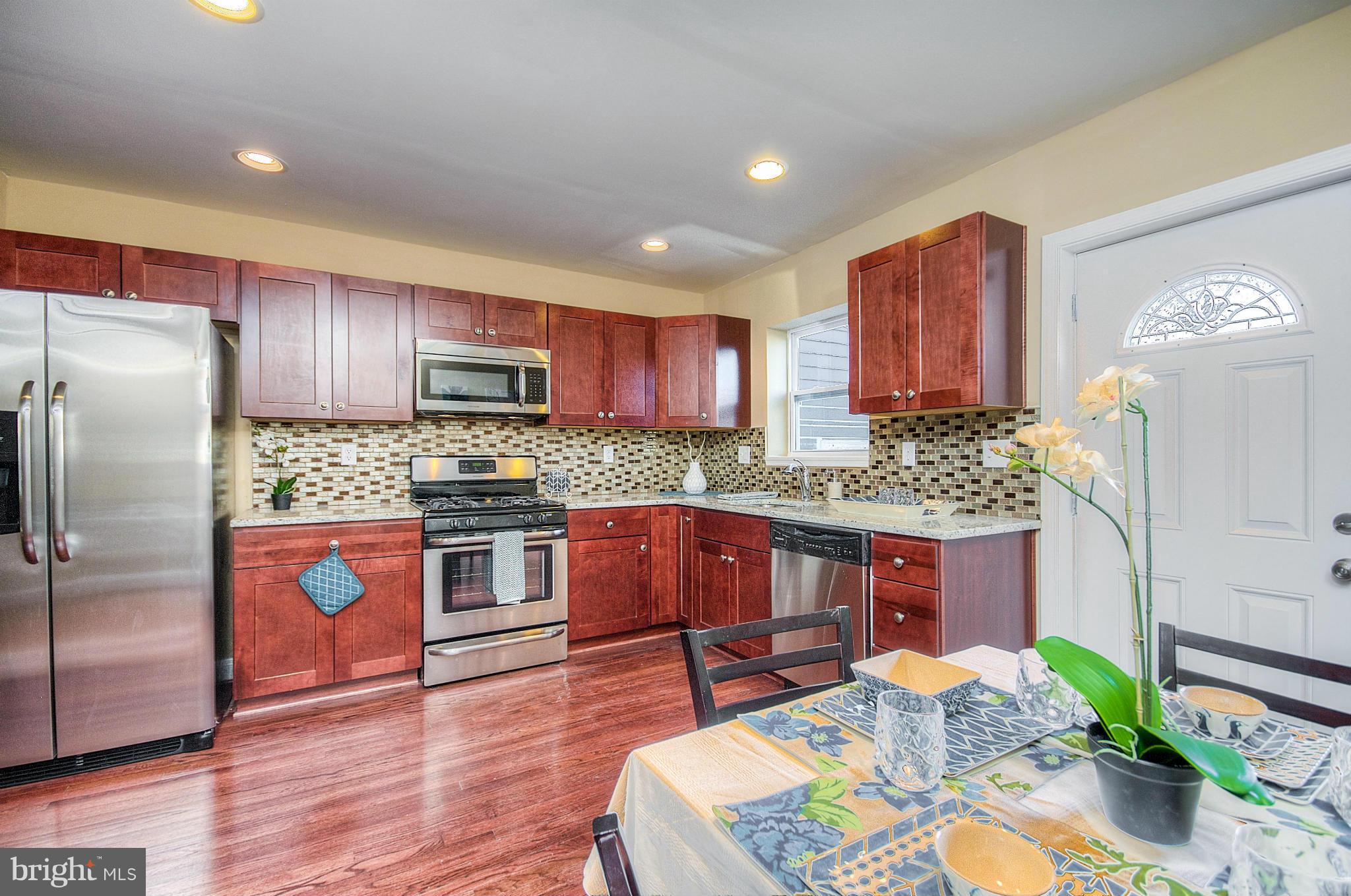 2159 Coralthorn Road Baltimore, MD 21220 - Photo 5 of 16 a kitchen with stainless steel appliances granite countertop a refrigerator a stove a sink a dining table and chairs with wooden floor