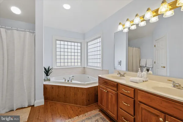 a spacious bathroom with a tub double sink and mirror
