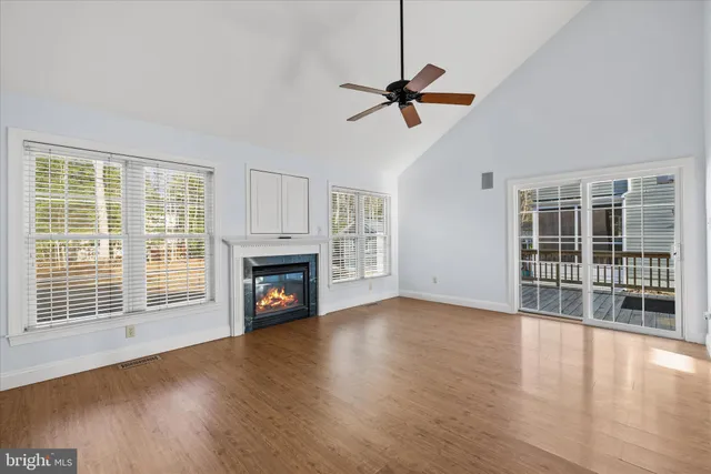 a view of an empty room with wooden floor fireplace and a window