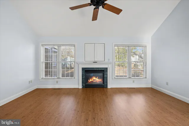 a view of an empty room with wooden floor fireplace and a window