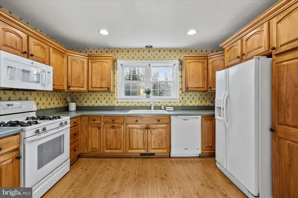 a kitchen with granite countertop a refrigerator a sink and white cabinets