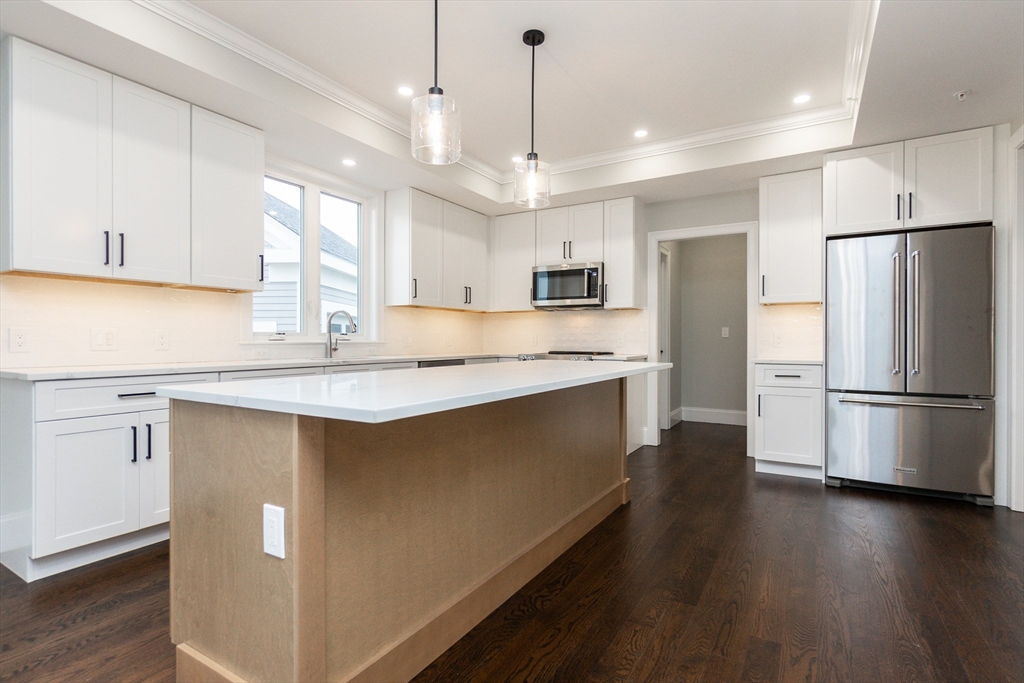 83 East Main Street Hopkinton, MA 01748 - Photo 10 of 42 a kitchen with kitchen island a refrigerator a sink dishwasher a stove and white cabinets with wooden floor