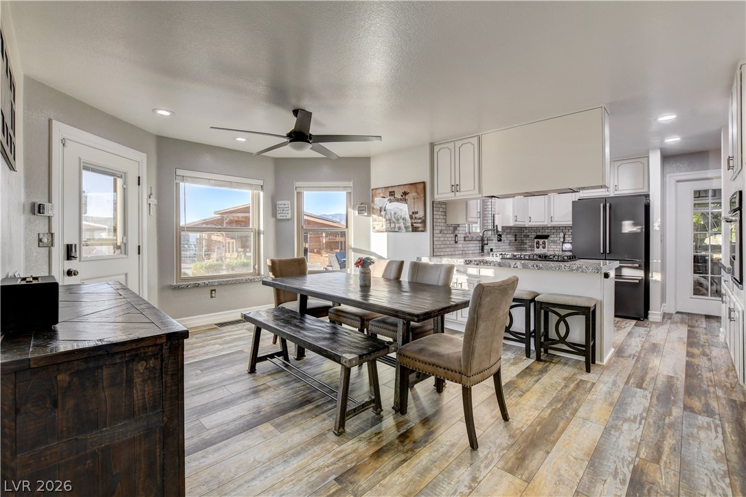 6460 Racel Street Las Vegas, NV 89131 - Photo 59 of 59 An open floorplan seamlessly connects the dining space to a modern kitchen with wood floors.