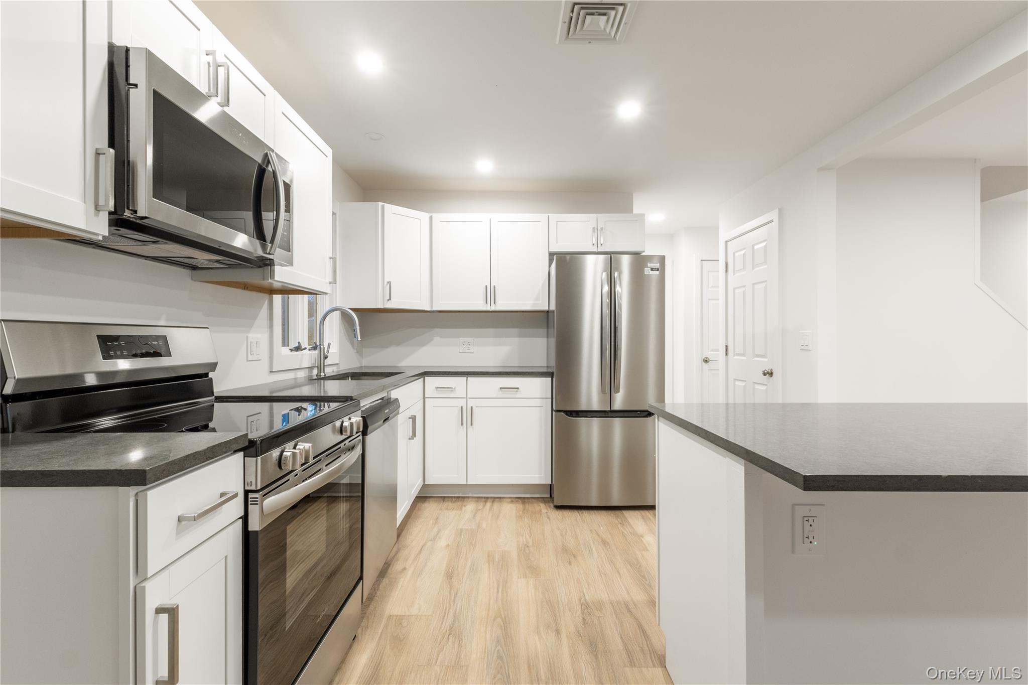 10 Overbrook Street Riverhead, NY 11901 - Photo 1 of 8 a kitchen with a sink a microwave a refrigerator and cabinets