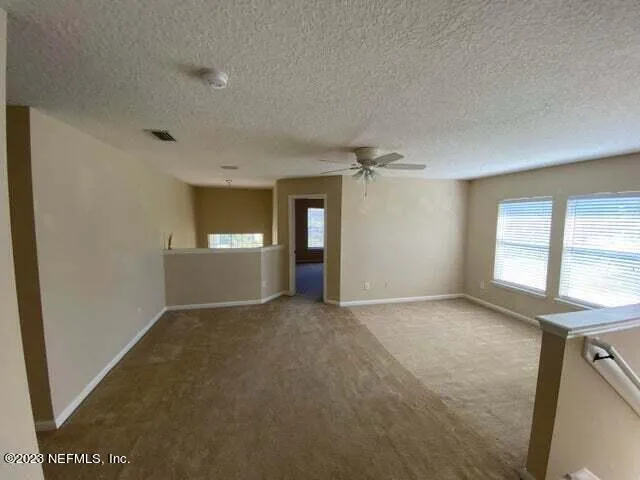 an empty room with windows and fan