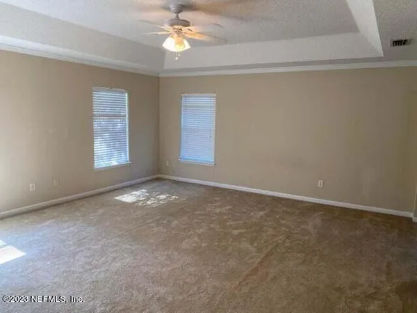 an empty room with windows and chandelier fan