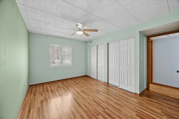 a view of empty room with wooden floor and fan