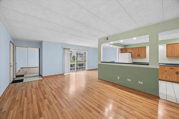 a view of a livingroom with wooden floor and a kitchen