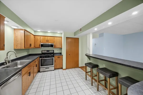 a kitchen with stainless steel appliances a sink a stove a refrigerator cabinets and a dining table