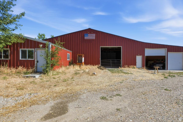 1634 West Arimo Road Arimo, ID 83214 - Photo 29 of 89 Red metal-sided barn featuring multiple large openings, including a tall, wide entry, and two additional garage doors