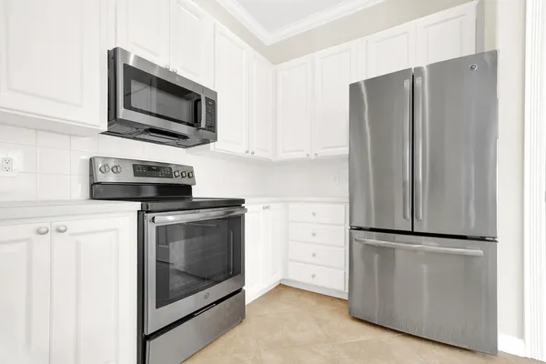 a kitchen with stainless steel appliances white cabinets and a refrigerator