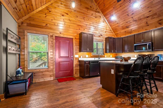 a kitchen with stainless steel appliances a stove top oven a sink a dining table and chairs