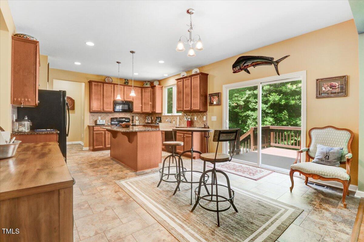 1304 Double Oak Lane Willow Spring, NC 27592 - Photo 15 of 46 a kitchen with stainless steel appliances kitchen island granite countertop a stove a refrigerator a sink a dining table and chairs with the floor