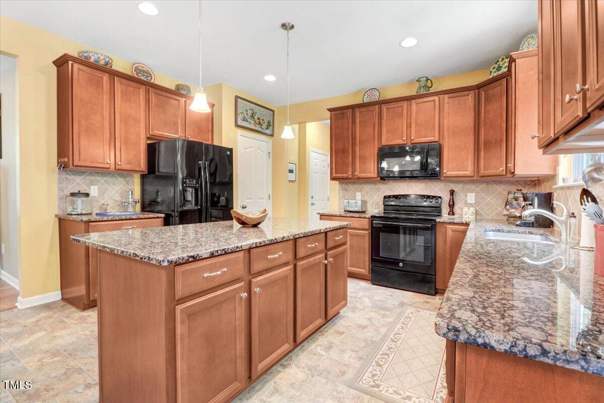 1304 Double Oak Lane Willow Spring, NC 27592 - Photo 18 of 46 a kitchen with stainless steel appliances granite countertop a stove top oven a sink dishwasher and a refrigerator with wooden cabinets