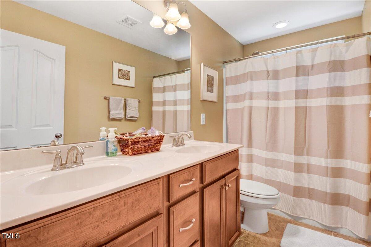 1304 Double Oak Lane Willow Spring, NC 27592 - Photo 30 of 46 a bathroom with a sink a toilet a mirror and shower curtain