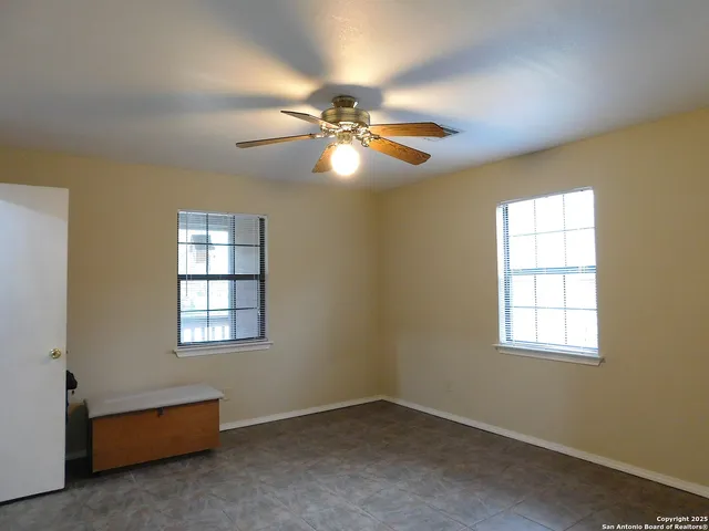 an empty room with windows and fan
