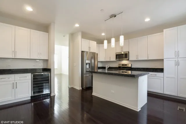 a kitchen with stainless steel appliances granite countertop a refrigerator a sink dishwasher a stove and white cabinets with wooden floor