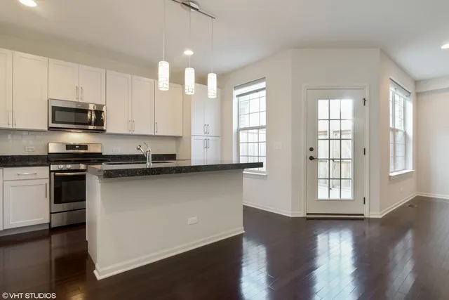 a kitchen with stainless steel appliances granite countertop a stove a sink and a microwave