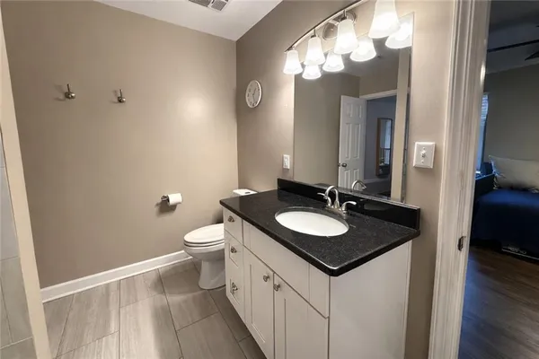 a bathroom with a granite countertop sink a toilet and a mirror
