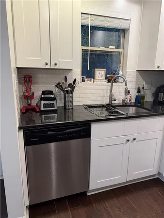 a kitchen with stainless steel appliances granite countertop a stove a sink and white cabinets