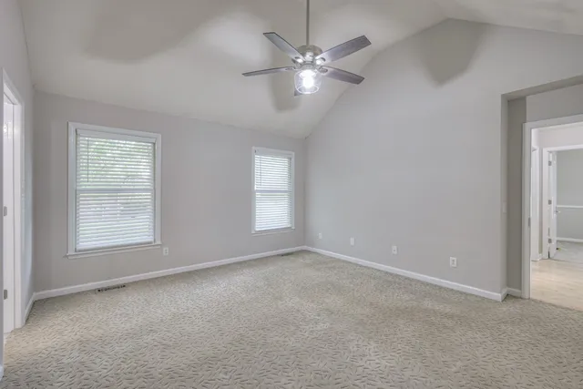 an empty room with windows and fan