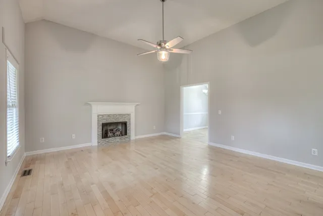 a view of an empty room with chandelier fan and fire place