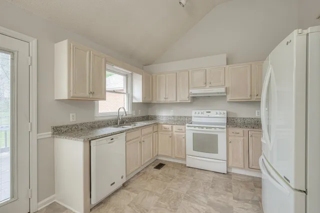 a kitchen with stainless steel appliances granite countertop a sink and dishwasher a refrigerator with white cabinets