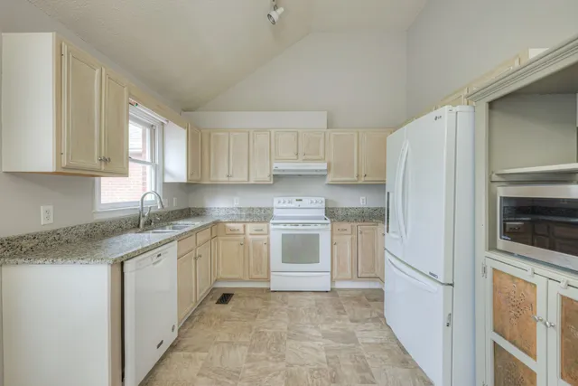 a kitchen with granite countertop a refrigerator sink and cabinets