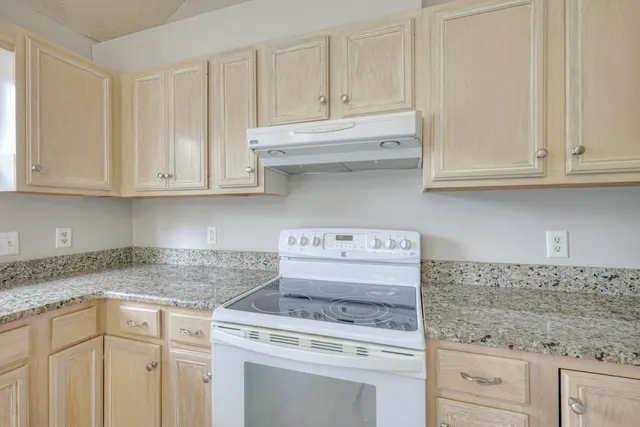 a kitchen with granite countertop white cabinets and a stove