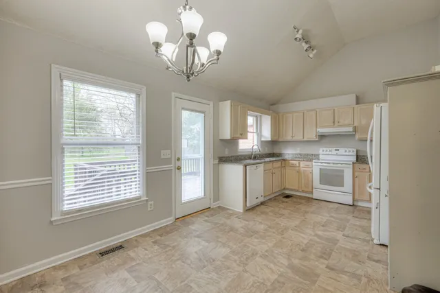 a kitchen with white cabinets and window