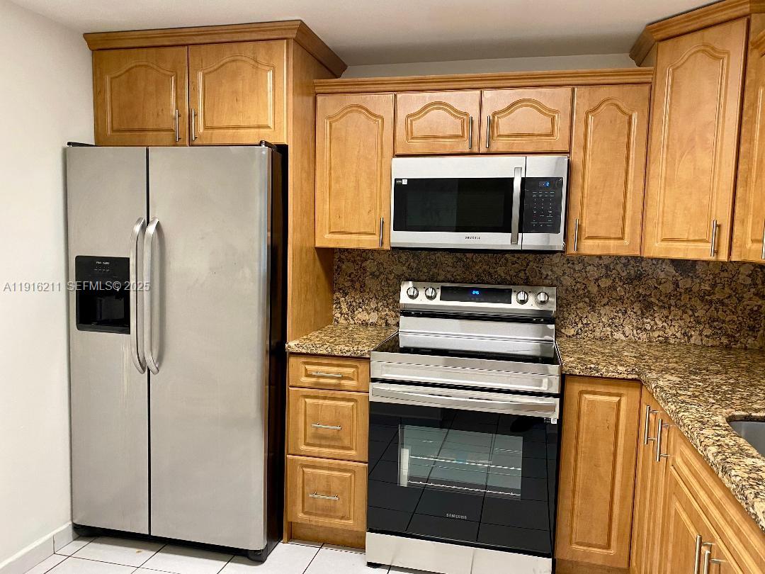 11287 Southwest 88th Street, Unit 209L Miami, FL 33173 - Photo 6 of 16 a kitchen with stainless steel appliances a stove a microwave and a refrigerator