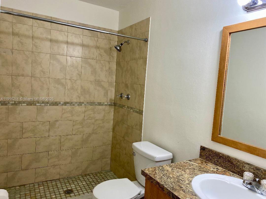 11287 Southwest 88th Street, Unit 209L Miami, FL 33173 - Photo 10 of 16 a bathroom with a granite countertop toilet a sink and shower