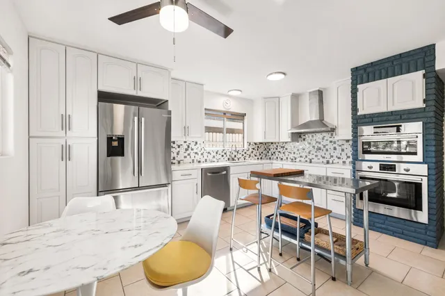 a kitchen with stainless steel appliances granite countertop a refrigerator and a stove top oven