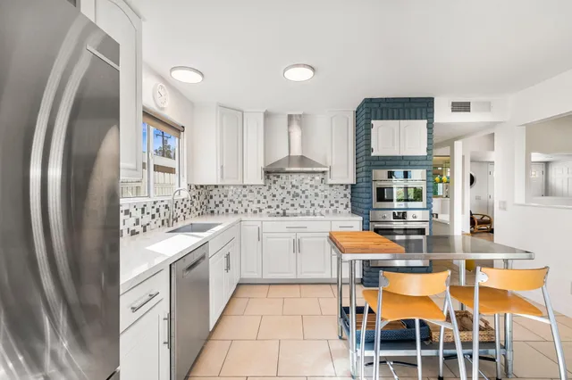 a kitchen with stainless steel appliances granite countertop a sink and a refrigerator