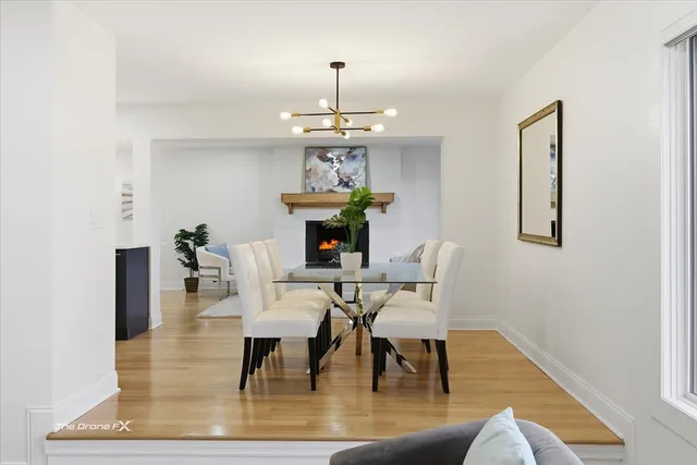 a dining room with wooden floor a chandelier a glass table and chairs