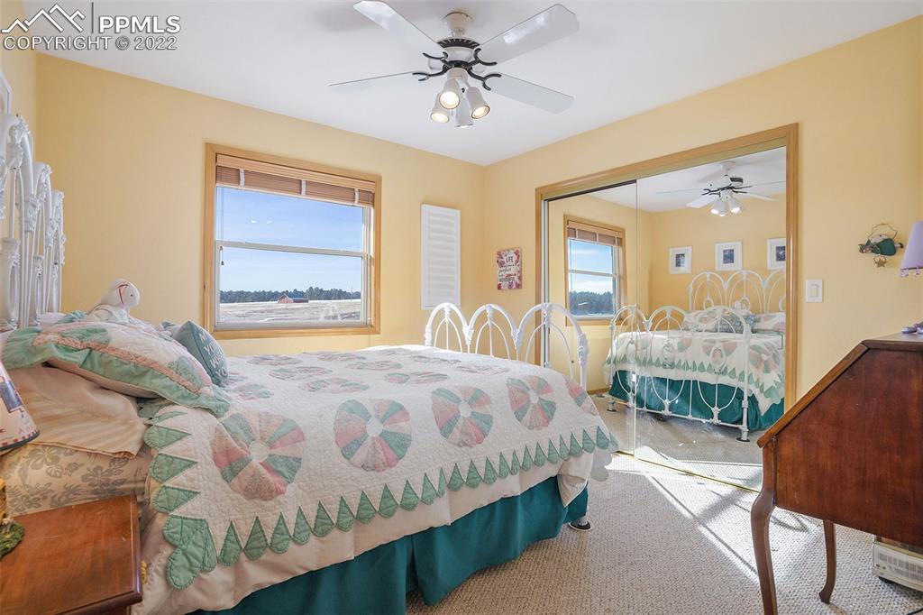 10695 Walker Road Colorado Springs, CO 80908 - Photo 16 of 49 a bedroom with a bed a table and large mirror