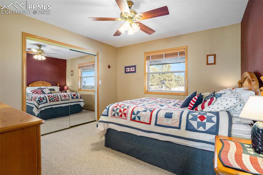 10695 Walker Road Colorado Springs, CO 80908 - Photo 18 of 49 a bedroom with a bed and a chandelier