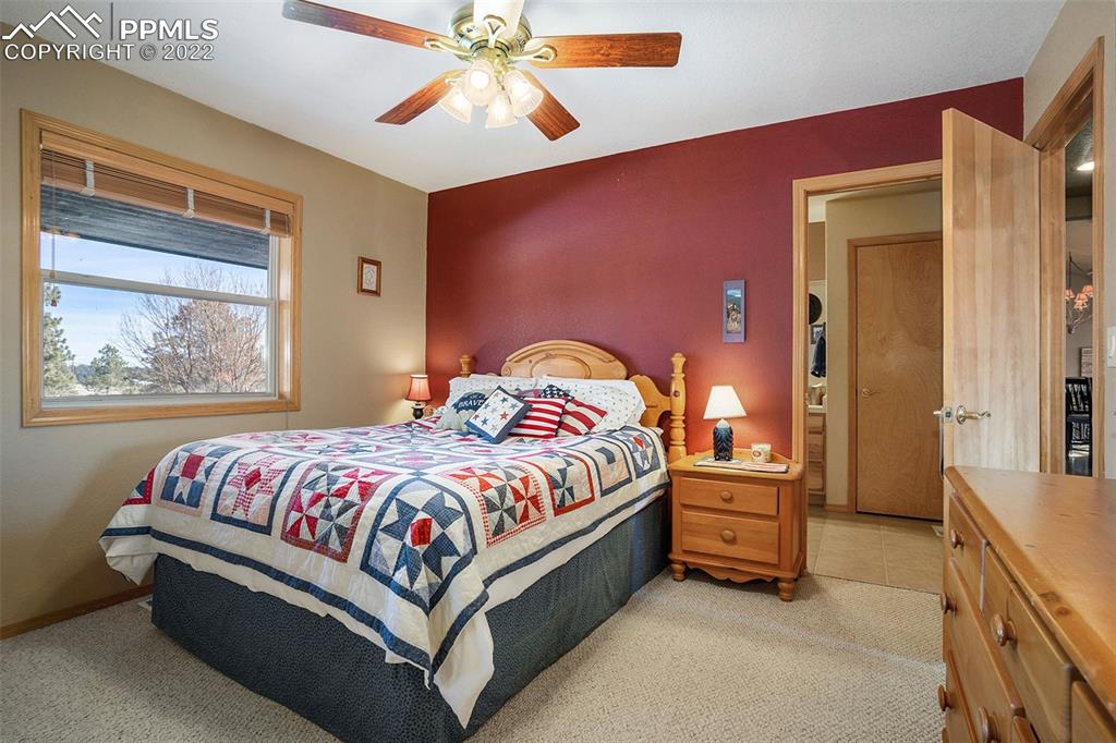 10695 Walker Road Colorado Springs, CO 80908 - Photo 19 of 49 a spacious bedroom with a bed and a chandelier