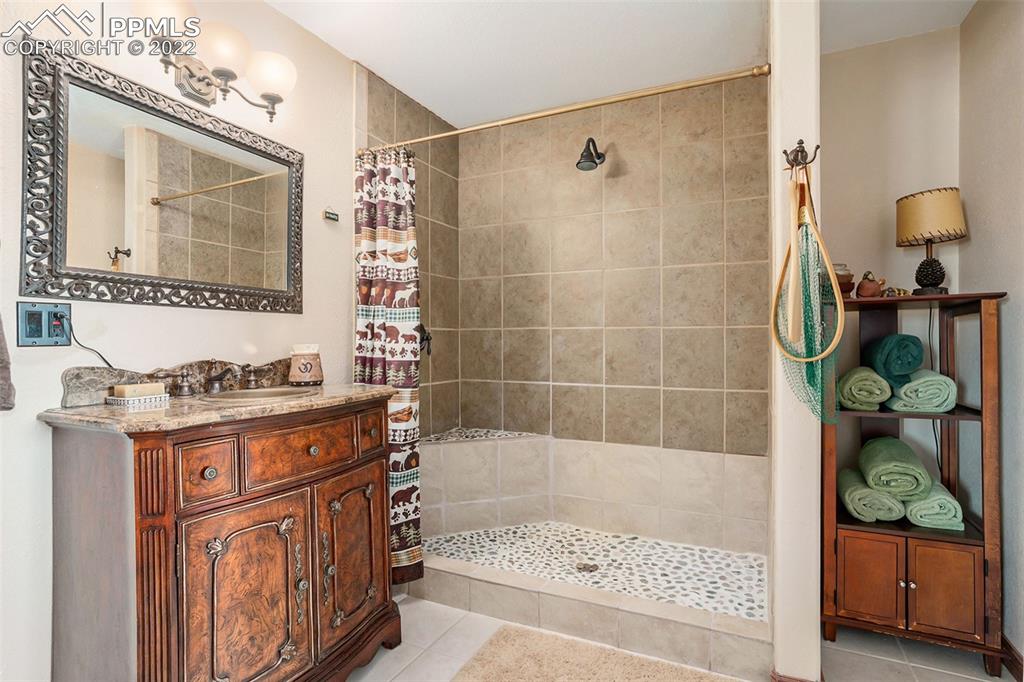 10695 Walker Road Colorado Springs, CO 80908 - Photo 28 of 49 a bathroom with a granite countertop sink a mirror a bathtub and shower
