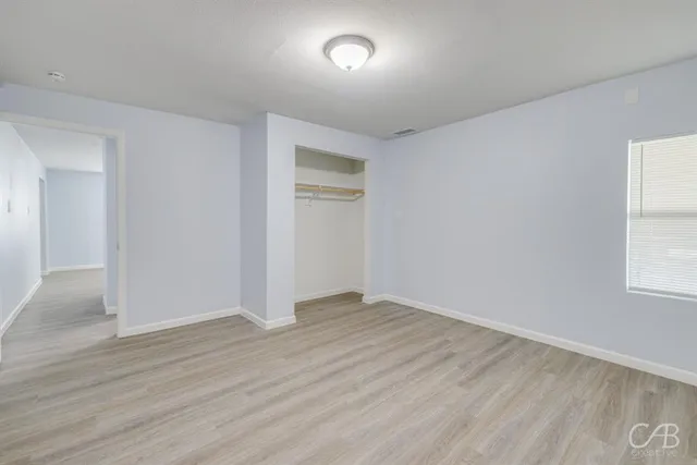 an empty room with wooden floor and windows