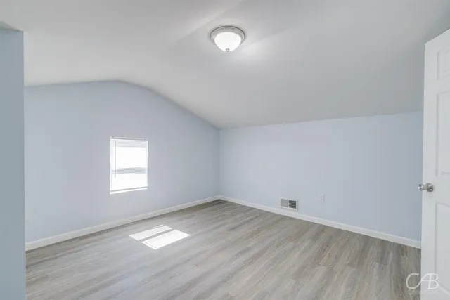 an empty room with a window and wooden floor