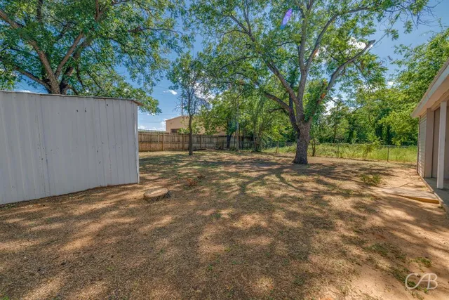 a view of a yard with wooden fence