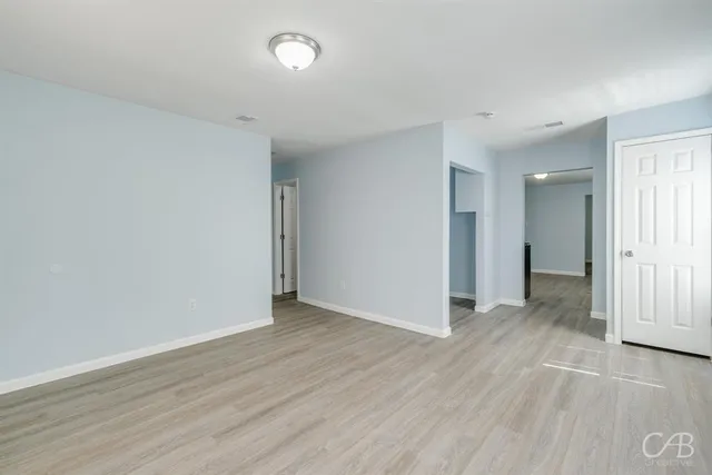 an empty room with wooden floor & windows and bathroom
