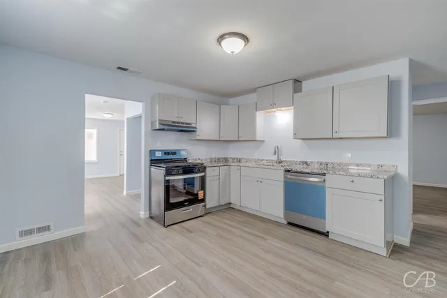 a kitchen with granite countertop a stove top oven a sink dishwasher and a refrigerator with wooden floor