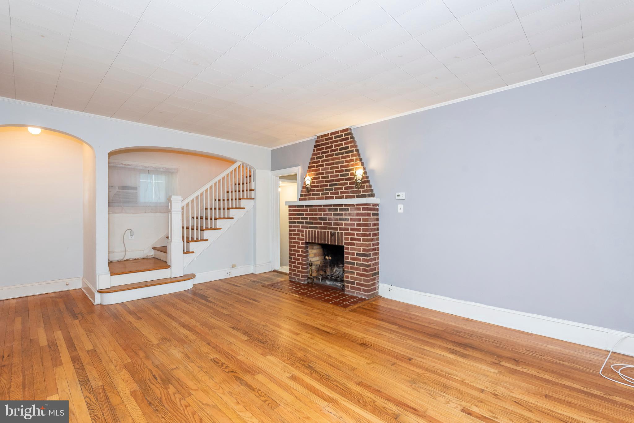 811 Dorchester Road Baltimore, MD 21229 - Photo 4 of 45 a view of an empty room with wooden floor fireplace and a window