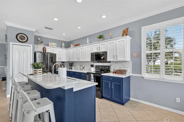 a room with stainless steel appliances kitchen island granite countertop a sink and cabinets